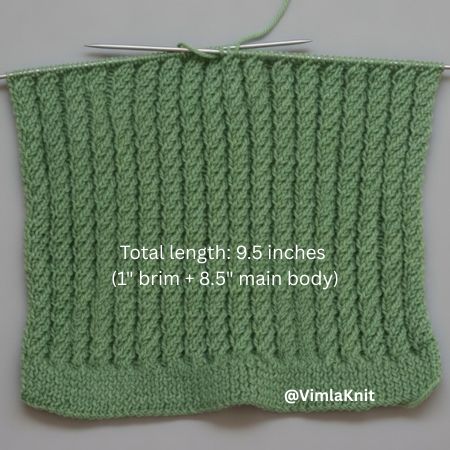 Spiral cable rib beanie knitting in progress: Sage green spiral cable rib stitch hat body on needles, total length 9.5 inches (1" brim + 8.5" main body), textured vertical ribs, beginner-friendly free pattern photo by @VimlaKnit.