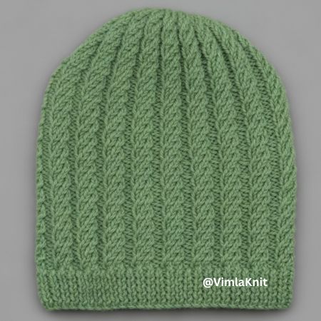 Sage green spiral cable rib beanie knitting pattern – finished handmade knit hat with ribbed brim, subtle twisting columns, displayed on gray background, free beginner pattern by @VimlaKnit.