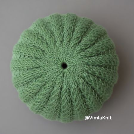 Sage green spiral rib beanie crown – beginner knitting pattern with twisting cable rib stitches from center, top view photo