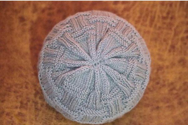 Top view of finished light blue-gray double basket rib stitch beanie showing beautiful star-shaped crown shaping. Hand-knitted unisex winter hat pattern by Vimla Negi.