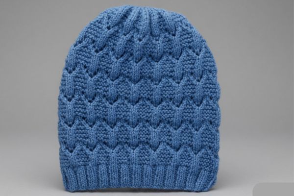 Soft blue lace knit beanie with diamond pattern and ribbed brim on gray background – Easy Knit Beanie Hat Pattern by Vimlaknit.