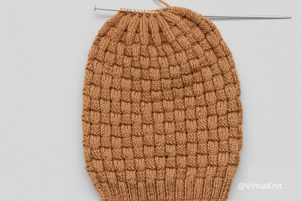 Camel brown basketweave knit beanie pattern with crown shaping still on the needles.