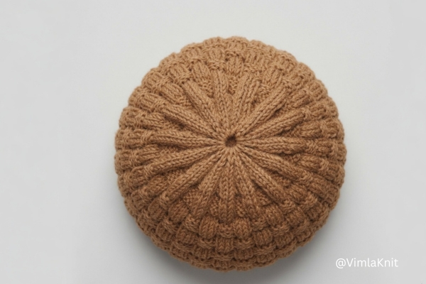 Camel brown basketweave knit beanie pattern with visible crown decrease and ribbed texture.