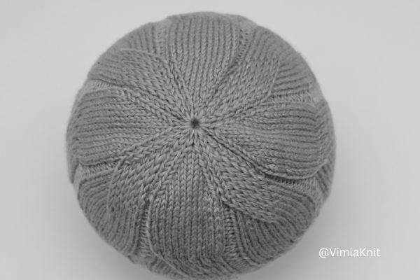 Gray cable beanie knit pattern showing crown decrease from top view.