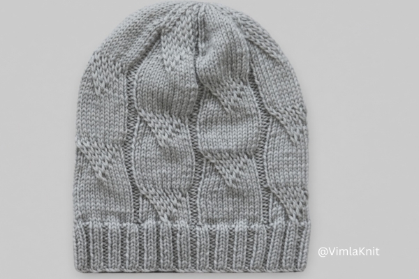 Gray cable beanie knit pattern with ribbed brim, front view.