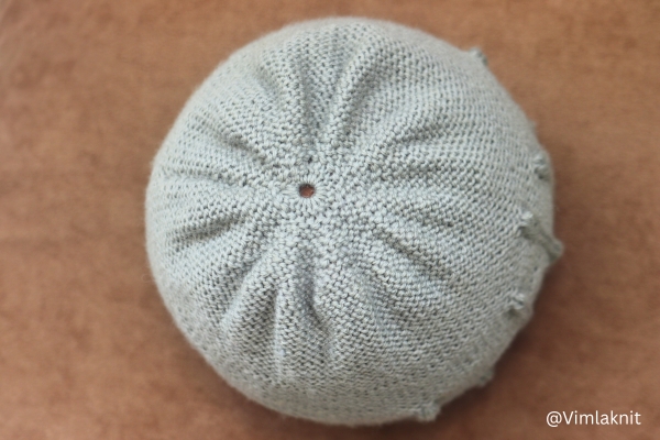 Top view of light sage green knit beanie showing crown decreases and center opening, leaf beanie knitting pattern